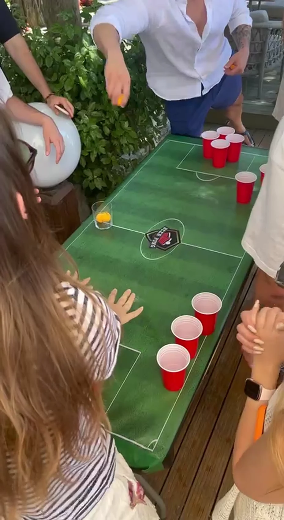 Bahçede beer pong masası etrafında toplanan katılımcılar